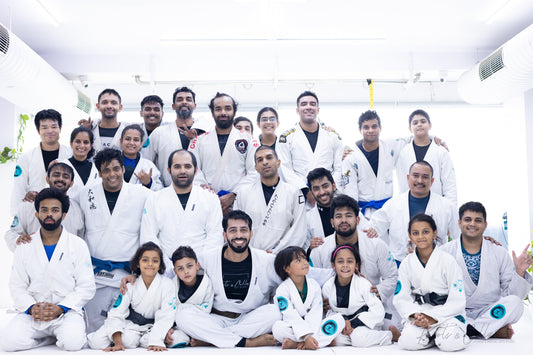 Knots & Collar BJJ academy group photo showing white, blue, and black belt practitioners together