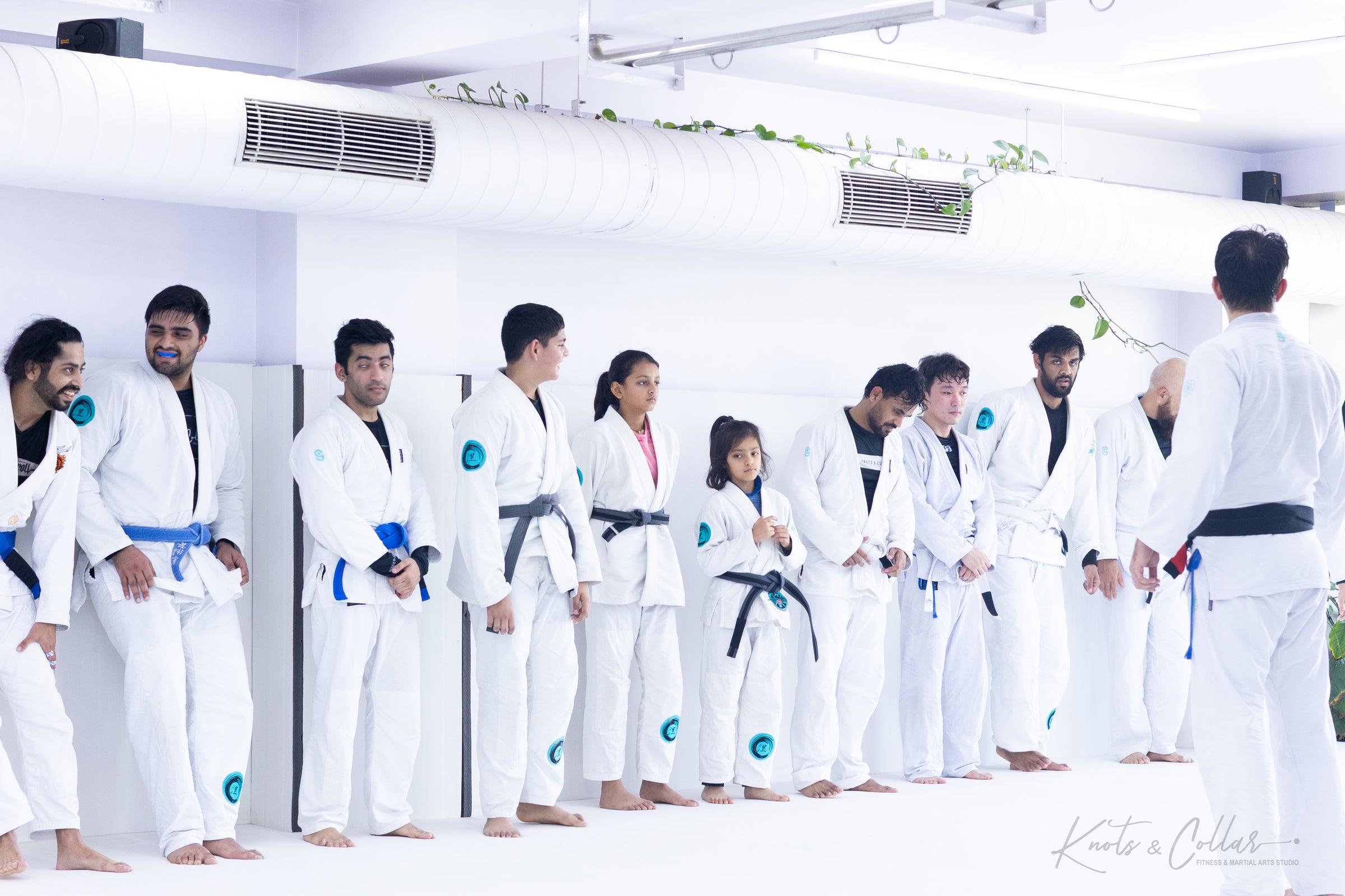 BJJ students at Knots & Collar listening to instruction, reflecting the academy's Kindness Over Toughness culture