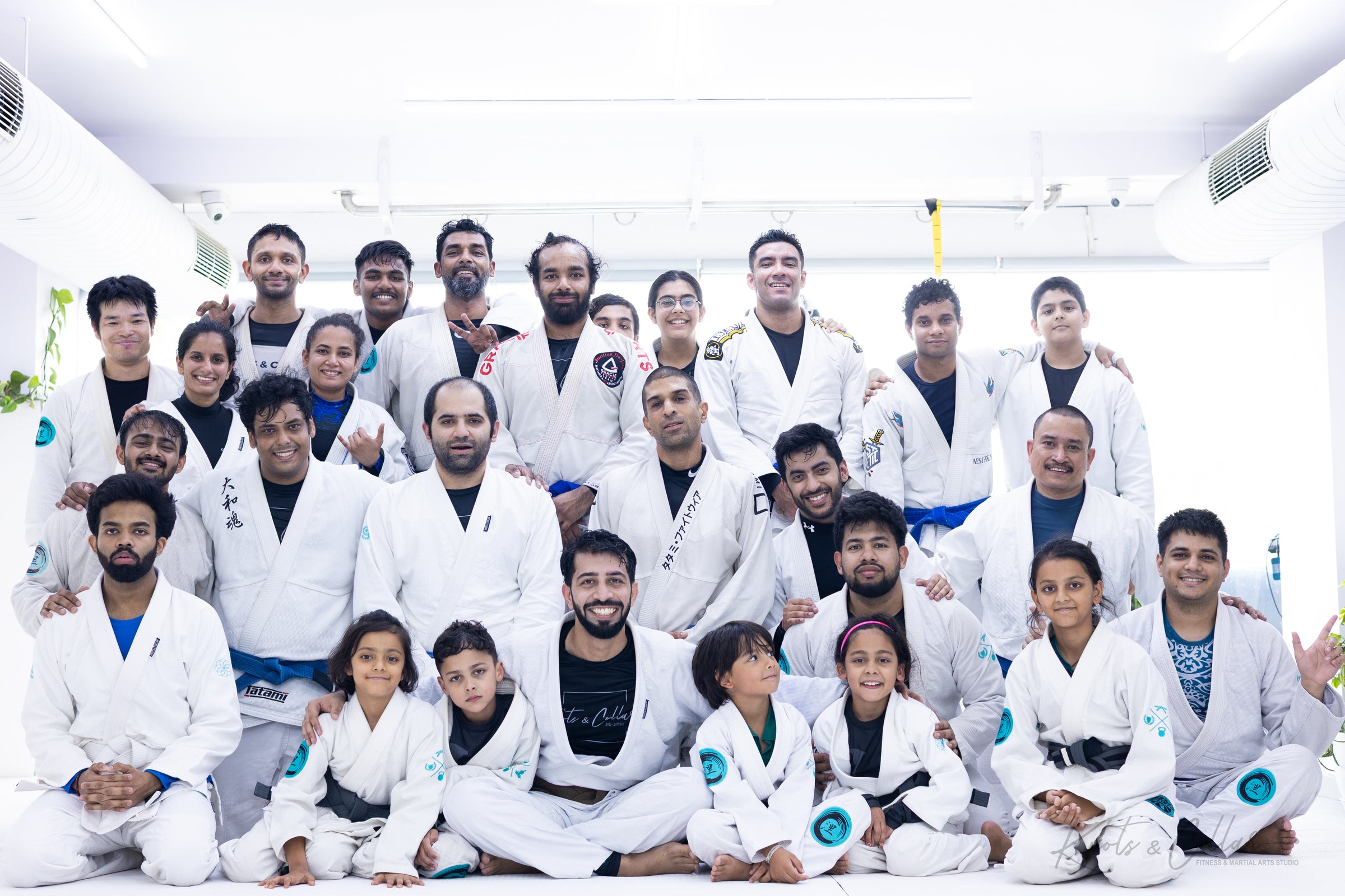 Knots & Collar BJJ academy group photo showing white, blue, and black belt practitioners together