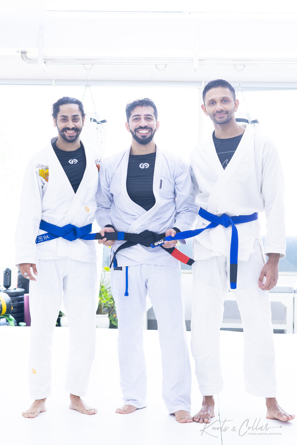 Multiple BJJ students receiving blue belt promotions in a ceremony at Knots & Collar