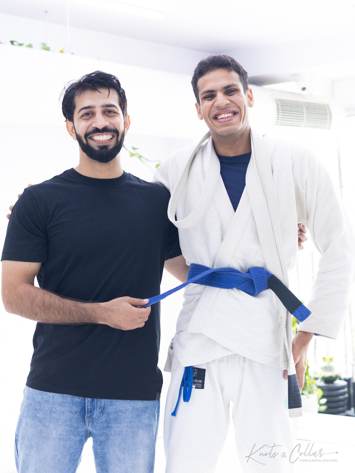 BJJ blue belt promotion ceremony — instructor tying the belt on a newly promoted student