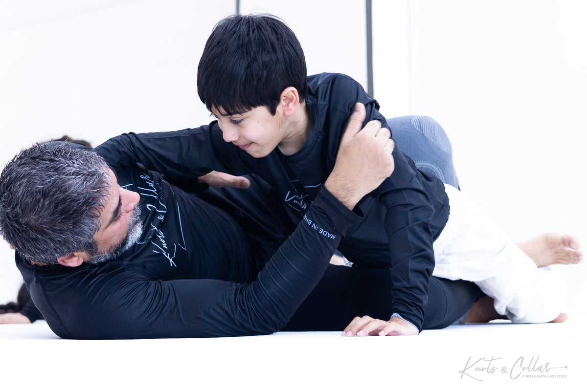 Instructor demonstrating a BJJ self-defence technique with a teenage student