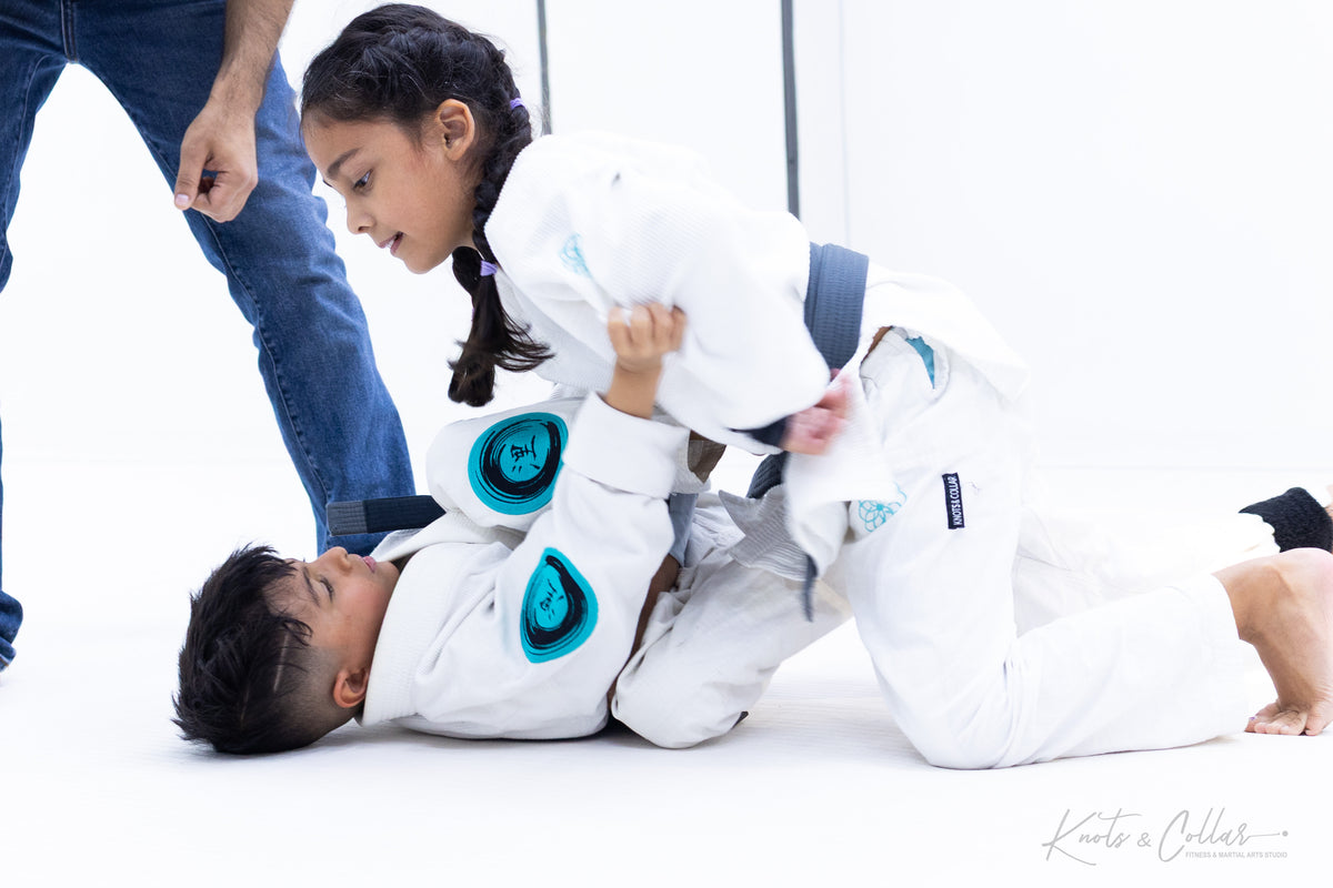 Girl practicing BJJ guard pass with instructor supervision at Knots and Collar Delhi